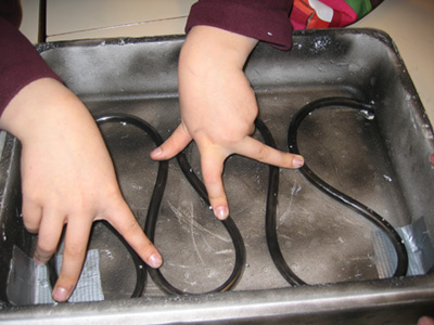 Foto: Kinderhände, die den
Schlauch auf den Behälterboden drücken